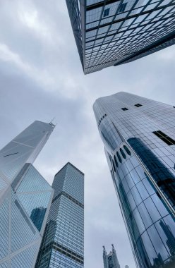 Hong Kong, Çin - 01 Şubat 2025: Bulutlu bir günde, Hong Kong 'un merkez iş bölgesinde alçak açılı gökdelenler. Görüntü bir seyahat hissi ve şehrin güçlü mimarisini sunuyor..