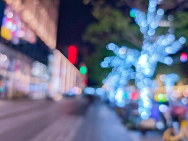 Bokeh ışıkları Çin 'de gece bir şehir caddesi boyunca yumuşak, rüya gibi bir etki yaratır. Sahne, bu şehir ortamında insanların olduğunu gösteriyor..
