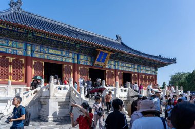 Pekin, Çin - 14 Eylül 2025: İkonik mavi çatısı ve karmaşık kırmızı cepheleriyle tanınan görkemli tarihi bir tapınak, parlak bir gökyüzü altında sayısız ziyaretçi çekiyor..