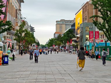 Pekin, Çin - 15 Eylül 2025: İnsanlar Pekin 'de çeşitli bina ve dükkanlarla çevrili canlı bir yaya sokağı olan Wangfujing boyunca yumuşak bir gökyüzü altında yürüyor.