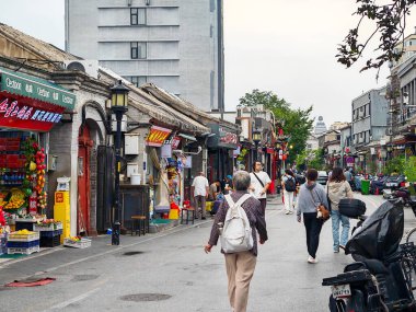 Pekin, Çin - 15 Eylül 2025: İnsanlar Pekin 'in tarihi Qianmen Caddesi boyunca yürüyor, geleneksel mağazaları ve mimarisi bulutlu bir gökyüzü altında..