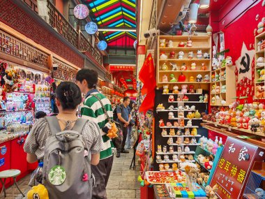 Pekin, Çin - 15 Eylül 2025: Müşteriler Pekin 'in tarihi Qianmen Caddesi' nde geleneksel bir çatı altında renkli hediyelik eşya ve ıvır zıvır dolu canlı bir market tezgahı keşfediyorlar..