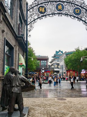 Pekin, Çin - 15 Eylül 2025: Pekin 'in Qianmen Caddesi: Geleneksel mimarisi, süslü kemer yolu, bronz heykeli ve hareketli yayaları ile tarihi kent manzarası.