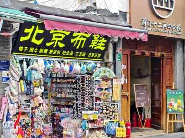 Pekin, Çin - 15 Eylül 2025: Pekin 'in hareketli Qianmen Caddesi' ndeki canlı dükkan cephesi, kırmızı tente altında renkli eşyalar, ayakkabılar ve çeşitli hediyeliklerle dolu..