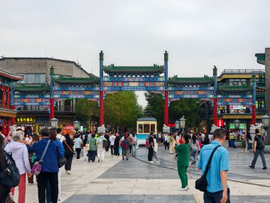 Pekin, Çin - 15 Eylül 2025: Pekin 'in Qianmen Caddesi' nde canlı bir sahne, güzel bir geleneksel kemer yolu, tarihi bir tramvay ve ziyaretçi kalabalığı sergileniyor..