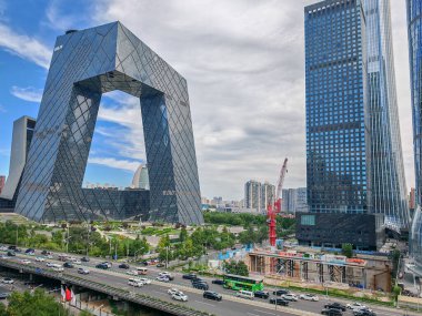 Pekin, Çin - 17 Eylül 2025: Benzersiz bir ticari bina olan belirgin CCTV Merkezi, kentsel otoyolları ve modern kuleleri olan dinamik bir şehir manzarası sunuyor.