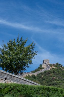 Pekin, Çin - 18 Eylül 2025: Pekin yakınlarındaki Çin Seddi 'nin tarihi bir bölümünde ziyaretçiler. Taş gözetleme kuleleri parlak gökyüzünün altındaki yemyeşil tepeleri taçlandırır..