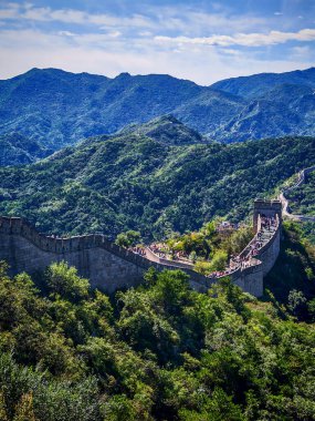 Pekin, Çin - 18 Eylül 2025: Tarihi Çin Seddi Çin 'in Pekin yakınlarındaki yemyeşil dağların arasından esiyor, parlak mavi bir gökyüzü altında, antik mühendisliğin bir kanıtı..