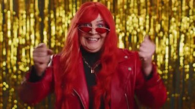 Deri ceketli mutlu bir kadın bağırıyor, el kol hareketi yapıyor başarıyı kutluyor, kazanıyor, doğum günü, piyango hedefini başarıyla tutturuyor. Parlak disko partisi geçmişi olan yaşlı bir büyükanne.