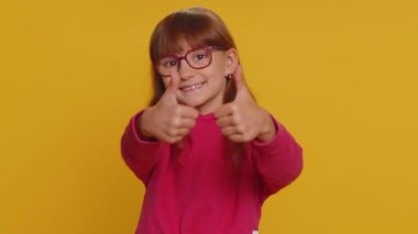 Like. Happy young preteen child girl kid looking approvingly at camera showing thumbs up, like sign positive something good, positive feedback. Toddler children isolated on studio yellow background