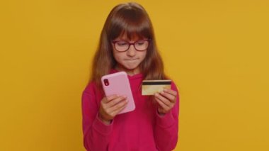 Genç bir çocuk kredi kartı ve akıllı telefon kullanarak para transfer ediyor, online alışveriş yapıyor, yemek siparişi veriyor. Küçük çocuklar stüdyo sarı arka planda yalnızlar.