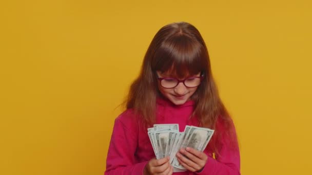 ガラスの豊かな喜びの若い幼児学校の女の子のファン 宝くじの勝者 大きな収入 富のようなお金のドルの現金紙幣を振って ティーン女性子供の子供上のスタジオ黄色の背景 — ストック動画