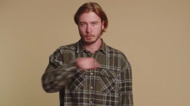 Reklamlara bak. Aşağıya bakan, abone olmamı söyleyen, el kol hareketi yapan, reklam amaçlı bilgi veren bir adam. Genç adam bej renkli stüdyo arka planında izole edilmiş.