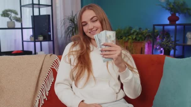 白种人快乐富家女的形象表现为浪费或手头上撒钱 多赚小费 大利润 中彩票 身体语言 年轻女人在家里沙发上的房间里 — 图库视频影像