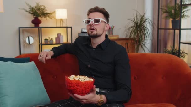 Opgewonden Man Met Een Baard Zittend Bank Popcorn Eten Kijken — Stockvideo