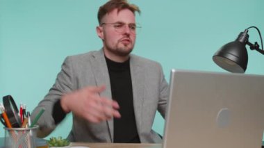 - Ne? - Neden? Sinirli genç iş adamı ofis masasında oturmuş öfkeli bir ifadeyle ellerini kaldırıyor, neden başarısız olduğunu soruyor, mavi stüdyo arka planındaki sorunlardan şüphe duyduğunu gösteriyor.