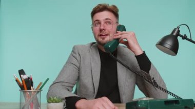 Kafası karışık sakallı iş adamının ofis masasında oturup 90 'lı yılların klasik telefonlarından konuşup aptal suratlar yapmasından bıktım. Hayal kırıklığı sohbeti. Mavi arka plandaki genç komik adam.