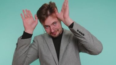 Komik, neşeli, samimi iş adamı, 20 yaşında ceketli, şakacı, aptal yüz ifadeleri takınan, suratını buruşturan, dil gösteren. Genç yakışıklı adam mavi duvarda tek başına.