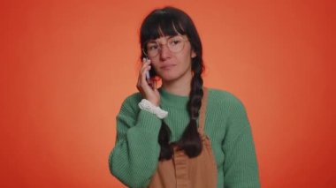 Uykulu serbest çalışan turist kadın arkadaşıyla cep telefonundan konuşuyor, internette sohbet ediyor. İlgisiz genç kız, turuncu arka planda izole akıllı telefondan can sıkıcı konuşmalar yapıyor.