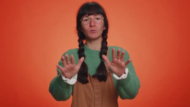 気をつけてね 指のジェスチャーを警告する若いオタクの女性は 危険を避けるために注意し アドバイスを与える 不承認記号を言う ラテン語の女の子オンオレンジ壁の背景 — ストック動画