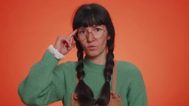 你疯了 年轻的书呆子女人 戴着眼镜 指着相机 摆出愚蠢的姿势 怪罪某个傻瓜的疯狂计划 在橙色工作室背景上被隔离的拉丁女孩 — 图库视频影像
