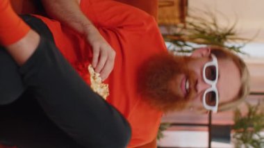 Heyecanlı genç adamın portresi kanepede oturup patlamış mısır yiyor ve evdeki ilginç televizyon dizileri, spor oyunları, filmler, çevrimiçi sosyal medya filmleri izliyor. Ev eğlencesi seven adam.
