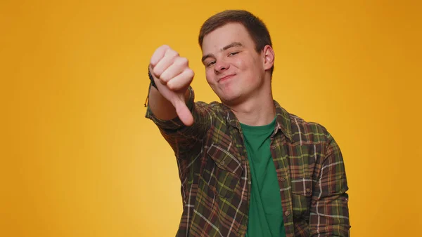 嫌いだ 嫌いを表現し 親指をサインジェスチャーを示すシャツの中で不幸なハンサムな男を動揺 若い大人の男の子 黄色の背景で撮影屋内スタジオ — ストック写真