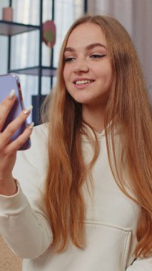 Beyaz kadın blogcu etkileyicinin portresi evde sosyal medya takipçileriyle telefon görüşmesi yapıyor. Mobil hoparlör vlog konuşmasından hoşlanan mutlu bir kadın. Dikey görünüm