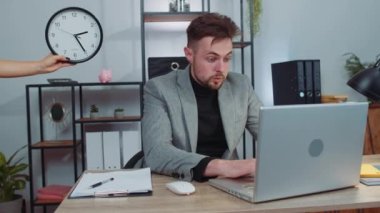Businessman programmer software developer working on laptop at office with anxiety checking time on clock, being in delay, deadline. Concentrated male freelancer business man worrying to be late