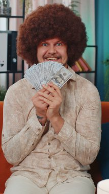 Zengin, yetişkin bir patron, hayran, başarılı iş kariyeri, piyango talihlisi, büyük gelir ve servet gibi banknotlar sallıyor. Evdeki kanepede oturan genç adam. Yaşam tarzı. Dikey görünüm