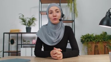 Bilgisayarda çalışan, kulaklık takan Müslüman iş kadını, serbest çalışan çağrı merkezi veya destek operatörü yardım hattı, ofiste müşteri veya iş arkadaşı ile hoş sohbetler yapıyor