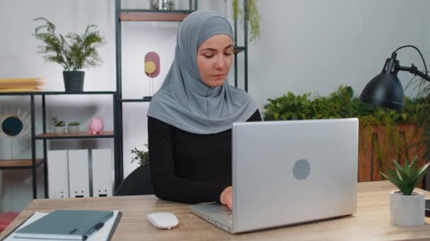 在总部完成工作后 在Hijab关闭笔记本电脑个人电脑的女商人 微笑着穆斯林经理自由职业者女孩忙着在网上工作 远程工作 电子学习 在笔记本上浏览互联网 — 图库视频影像