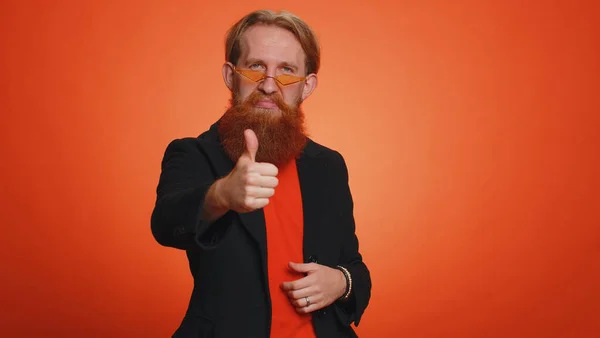 身穿黑色夹克的红头发男人竖起大拇指同意某事或给予肯定的回答推荐广告喜欢好的 一个人孤零零地躺在橙色工作室里 — 图库照片