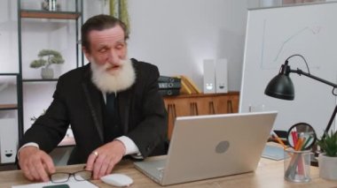 Yaşlı iş adamı güneş gözlüğü takıyor, şenlik şapkası takıyor iş yerinde şampanya içiyor zafer dansı yapıyor, hafta sonu. Proje geliştirme sevinci. Başarıyı kutluyoruz. Piyango ikramiyesi. Ofisteki insanlar