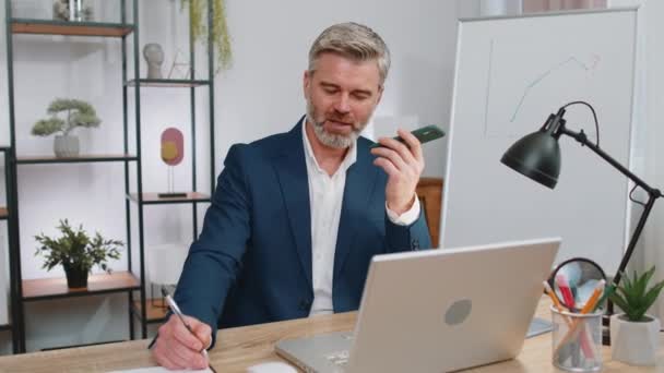 Olgun Adamı Çalışıyor Cep Telefonu Hoparlörleri Ofiste Dizüstü Bilgisayarla Konuşuyor — Stok video
