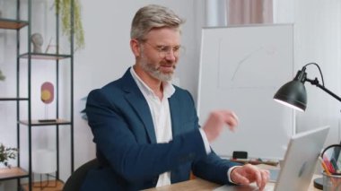 Olgun iş adamı ofis masasında oturuyor ve işini bitirdikten sonra bilgisayarı kapatıyor. Orta yaşlı serbest çalışan, uzaktan kumandalı bir adam. Defter bilgisayarında e-öğrenme, internette gezinme