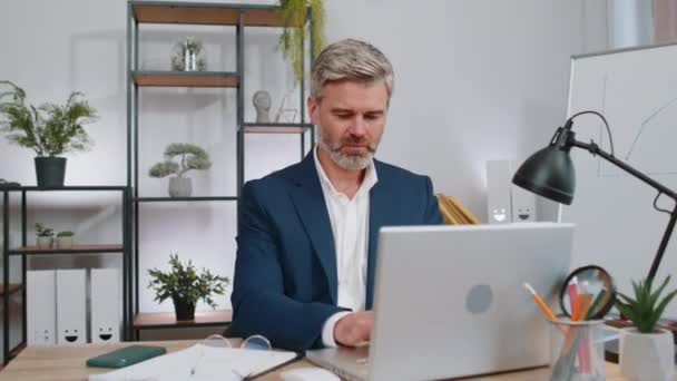 君を選んだ 中年のビジネスマンプログラマーソフトウェア開発者のオフィスノートパソコンのカメラを指して作業し 幸せな表情で見て 選択をし 方向性を示す 成熟したフリーランスの男 — ストック動画