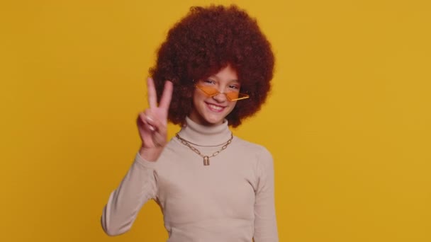 快乐的少女女孩表现出胜利的迹象 希望成功和胜利 做和平的姿态 带着善意的乐观的表情 在工作室黄色背景上被隔离的有趣的小孩 — 图库视频影像