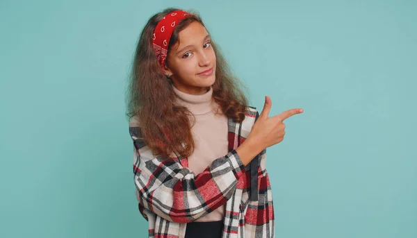 12岁以下的小女孩快乐的展示拇指指向空旷的地方 商业广告区的文字 复制空间的商品促销 十几岁的孩子 蓝墙背景图 — 图库照片