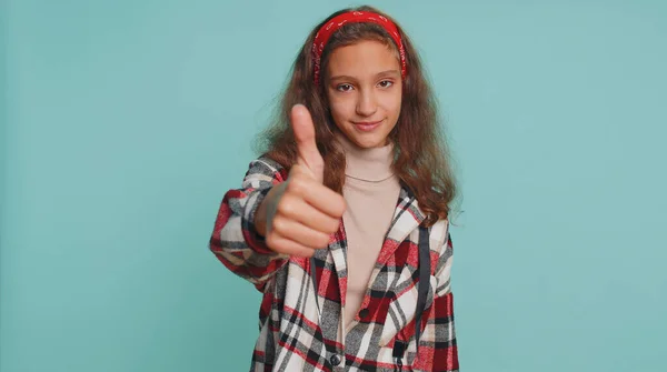 Great job, nice work. Young teenager child girl kid showing thumbs up and nodding in approval, successful good work, victory, win, lottery jackpot. Preteen children isolated on studio blue background