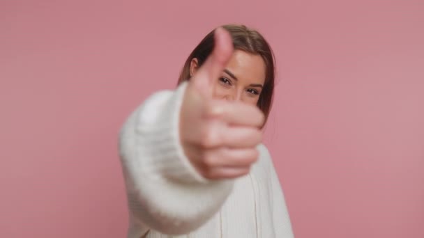 穿着白色毛衣的嬉皮士美女竖起大拇指同意某事或给予肯定的回答推荐广告喜欢好的 在粉红工作室背景下孤身一人的小女孩 — 图库视频影像