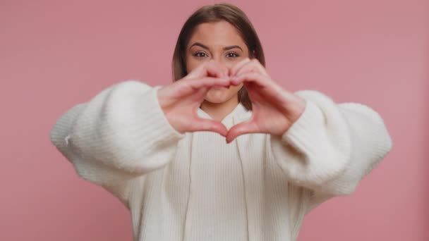 恋の女 白いセーターを着た笑顔の女性20代の心のジェスチャーは 愛のサインが良い感情と同情を表現しています 若いです可愛いです大人女の子絶縁一人でピンクスタジオ背景 — ストック動画