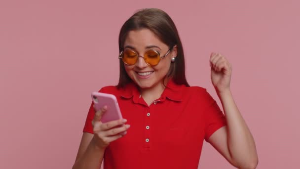 快乐快乐快乐的女人穿着便衣红衫用手机打字大声喊着 发现了巨大的胜利 好消息 彩票目标实现了 庆祝成功 — 图库视频影像