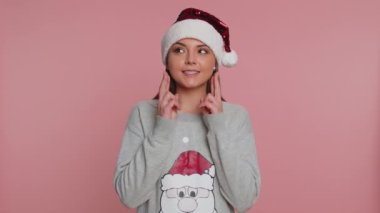 Noel Baba süveteri giyen genç bir kadın Noel tatilini hediye kutluyor ve sevinçle gülümsüyor. Beklenmedik güzel hediyelerden memnun kalmış gibi görünüyor. Pembe stüdyo geçmişi olan kız.