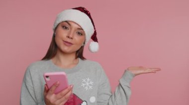 Noel Baba Maddesi süveteri giyen genç bir kadın akıllı telefon kullanıyor. İnternette yeni bir yazı yazıyor, tarıyor, araştırıyor, olumlu geri bildirim gibi başparmakları var. Tavsiyeler, mesaj için boş bir reklam alanını işaret ediyor.