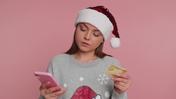 精明的圣诞女性顾客在汇款时使用信用卡和智能手机 在网上购物 金融和互联网 在粉色背景下孤身一人的小女孩 — 图库视频影像