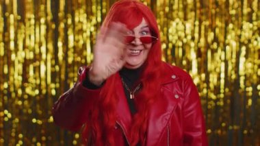 Buraya gel, bize katıl. Hoş geldiniz. Olgun stil sahibi bir kadın elleriyle davetkar bir jest yapıyor, katılmak istiyor, gelmek için işaret ediyor, merhaba ya da elveda diyor. Parlak disko partisi geçmişi olan büyük anne.