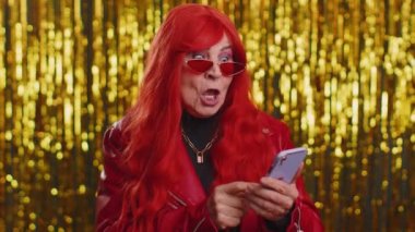 Mutlu, ceketli yaşlı bir kadın cep telefonu kullanıyor. Daktilo kullanıyor. 