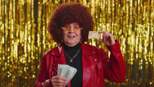 お金のキャッシュレスを転送するプラスチッククレジットカードの広告を示す幸せな老婦人は オンラインショッピング 販売割引 インターネット注文配信購入を購入します 輝く壁の上のシニア祖母 — ストック動画