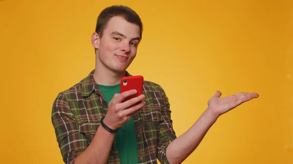 英俊的男人用智能手机在网上打印新的帖子 竖起大拇指 指出空旷的地方 商业广告区 复制商品促销空间 小男孩 — 图库照片